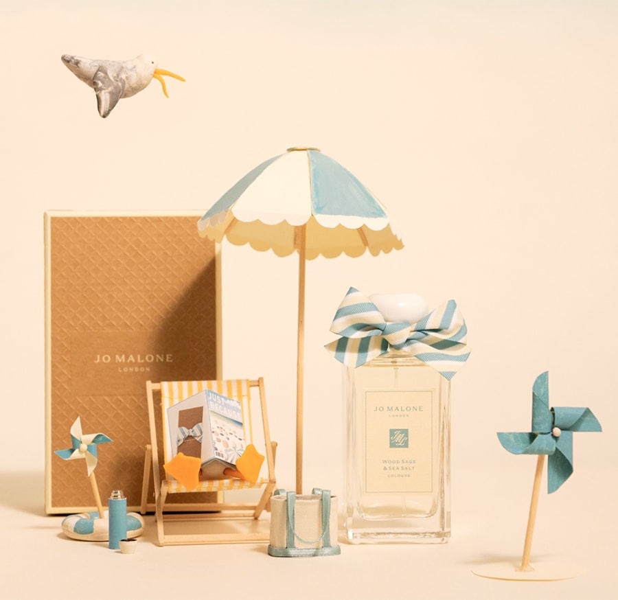 A stop motion video shows a seaside scene with a seagull on a deckchair next to a cologne and blue and white beach accessories. 